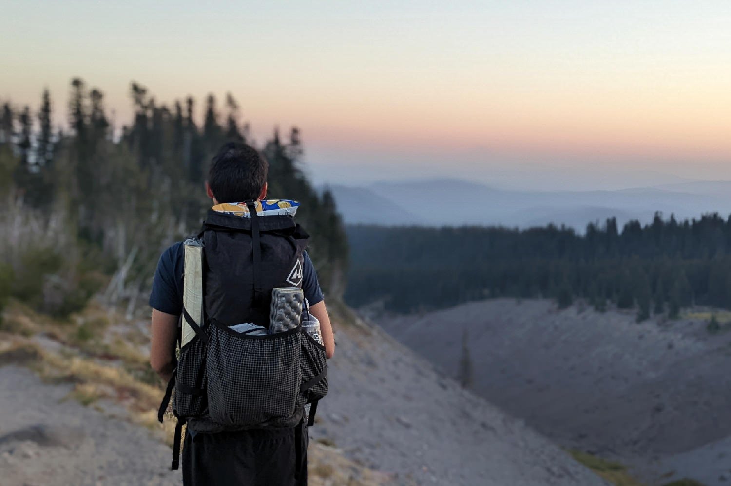 backpacker with their backpack on hiking into the sunset. 