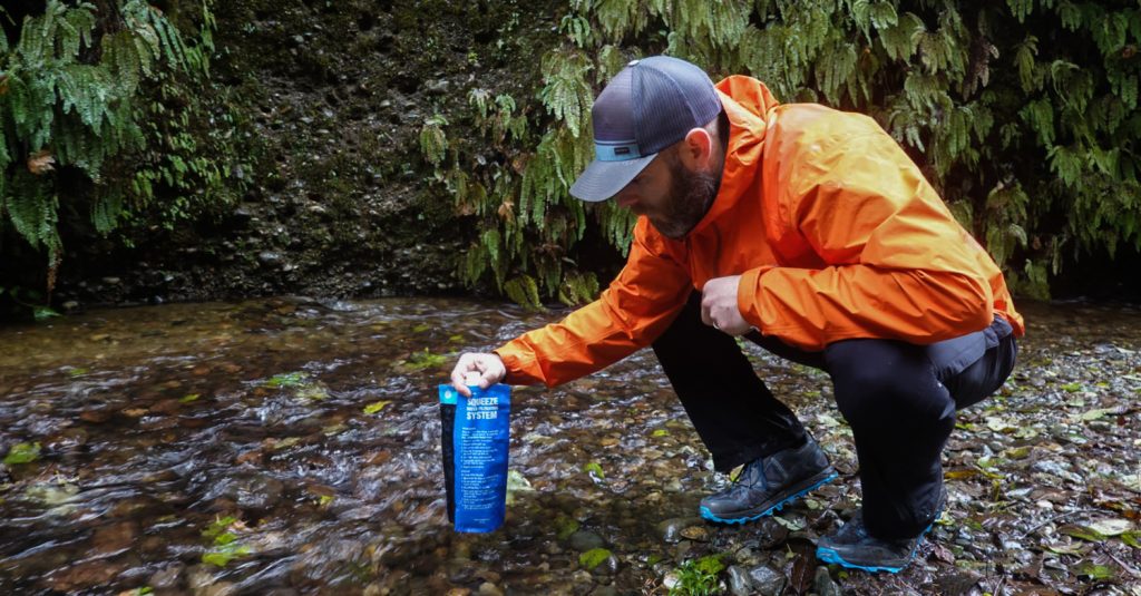 Backpacker filling his sawyer squeeze pouch from a stream