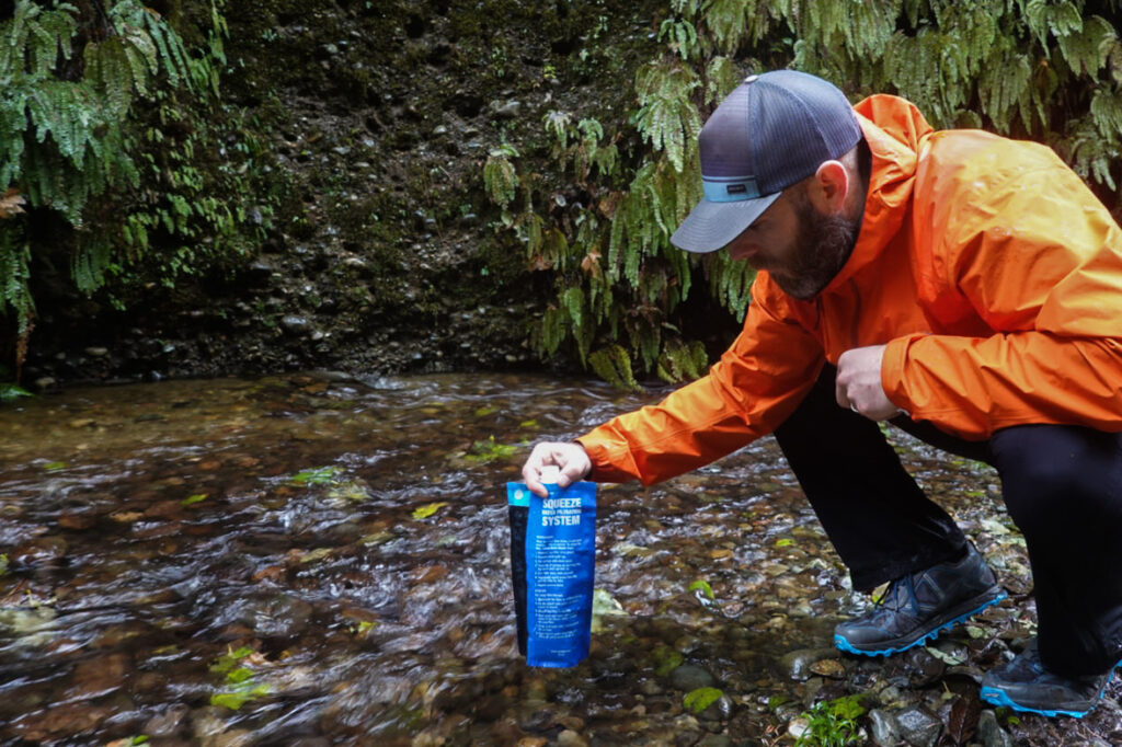 Backpacker filling his sawyer squeeze pouch from a stream