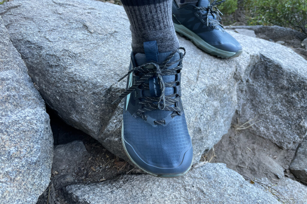 close up of a hiker wearing altra lone peak 8's on small boulders