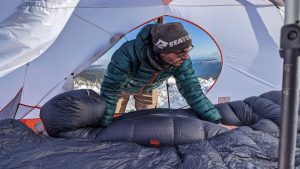 A hiker situating a sleeping bag in a 4-season tent on a winter camping trip