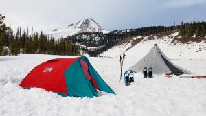 two tents pitched in the snow with mt hood in the distance