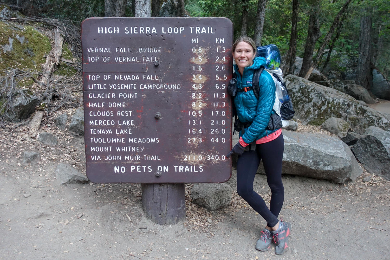 hiker posing in front of a yosemite national park trail information sign