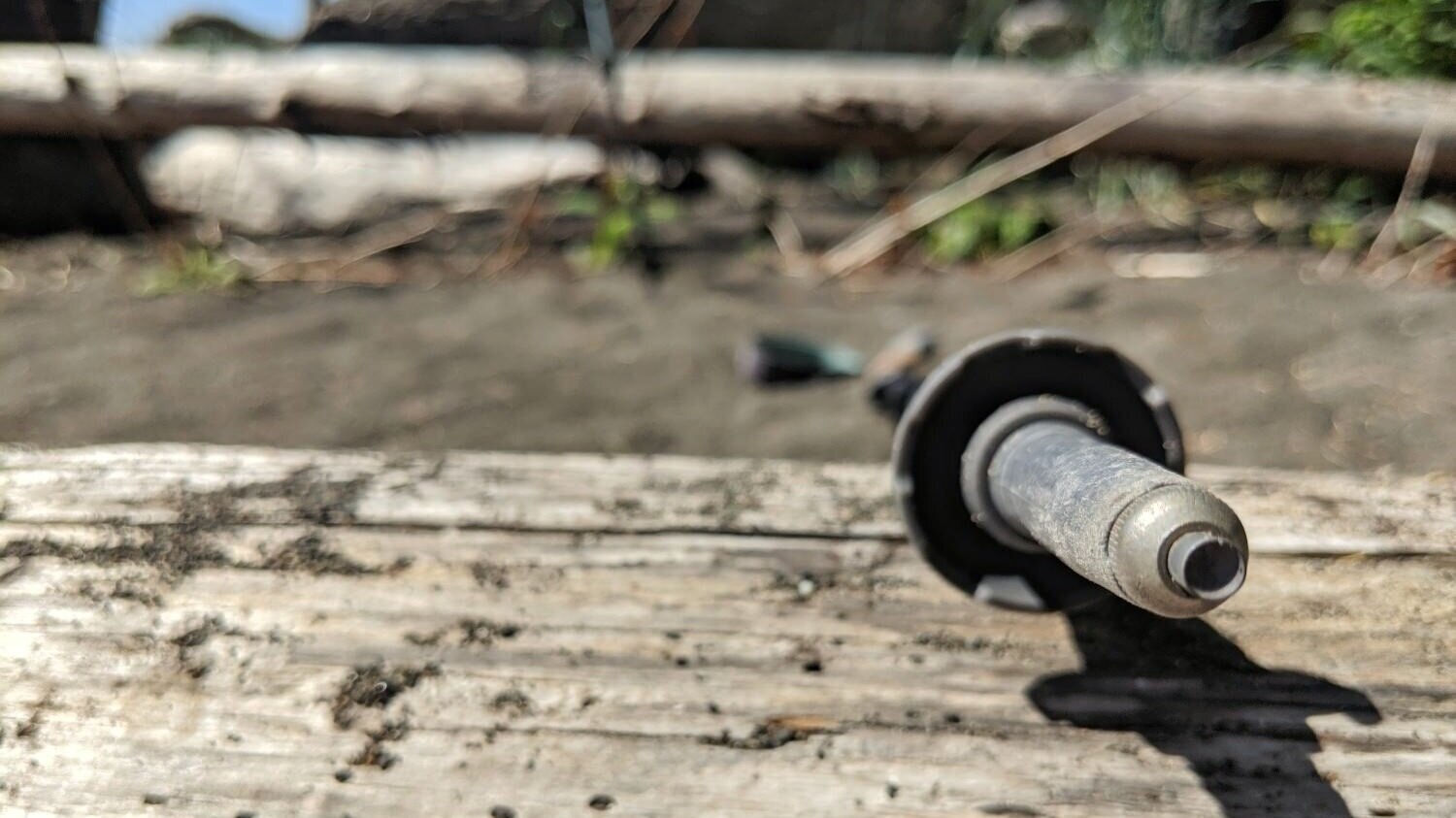 the view of the carbide tip of a trekking pole resting on a log