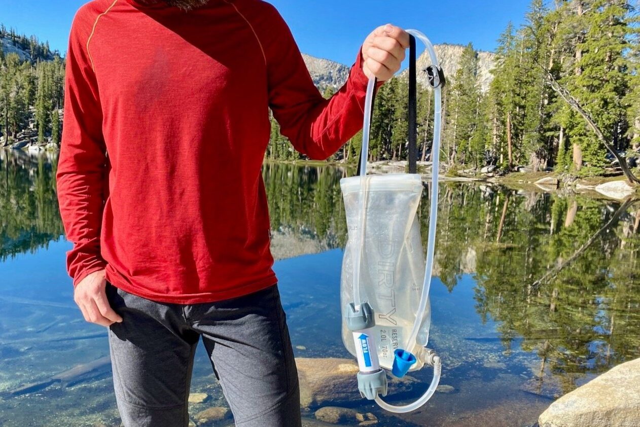 a backpacker in yosemite holding up their treated and clean drinking water in a Platypus Gravityworks bladder