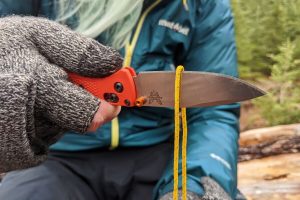 A close up of a person cutting a rope with the Benchmade Bugout Mini Pocket Knife