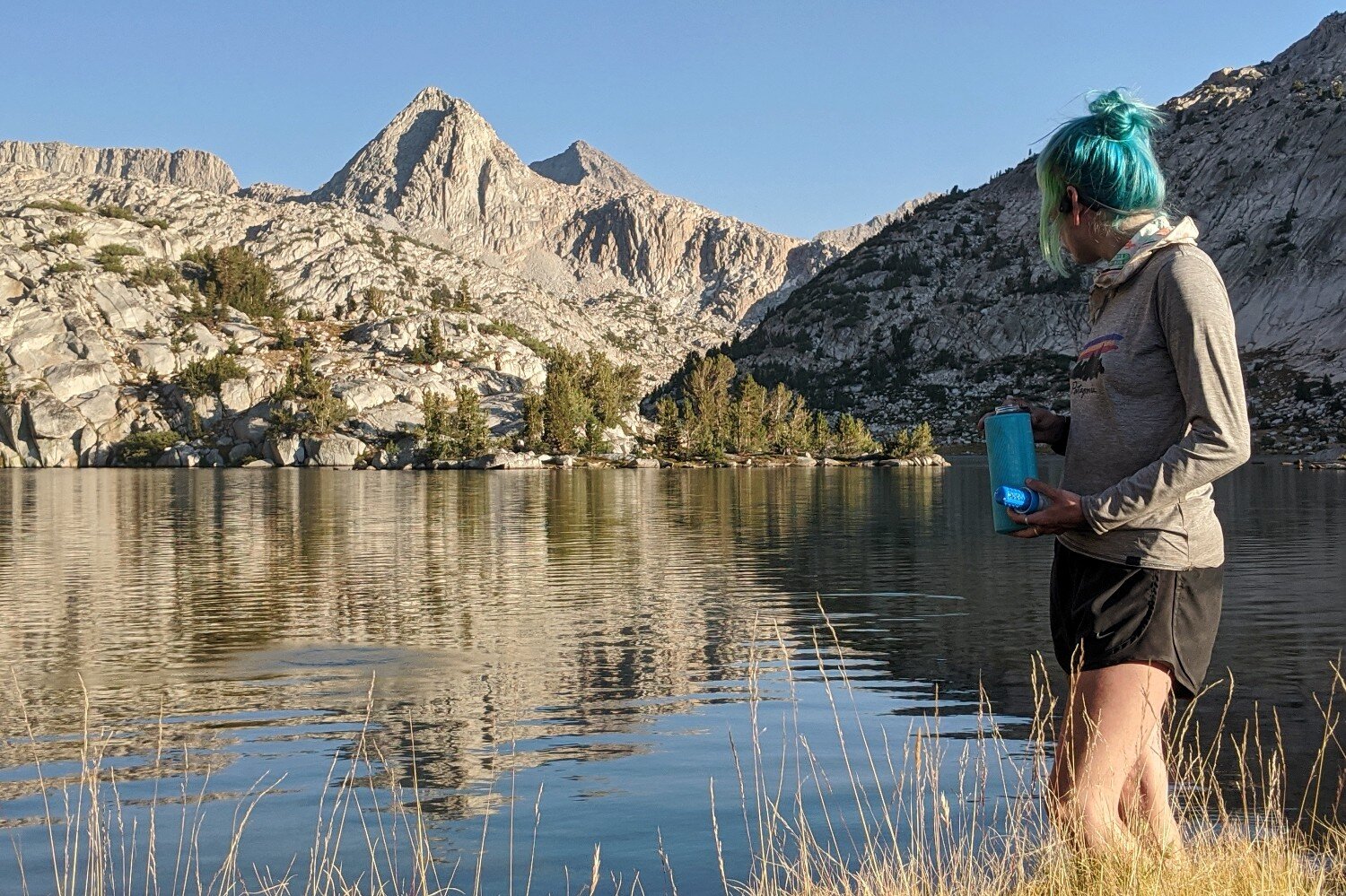 https://www.cleverhiker.com/wp-content/uploads/2023/08/A-hiker-standing-by-a-lake-and-mountains-holding-a-water-bottle-and-the-Katadyn-BeFree-Water-Filter.jpeg