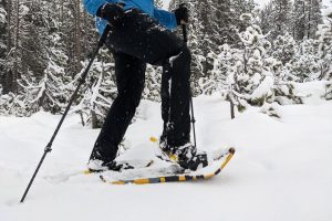 a man walking through snow in the atlas montane snowshoe