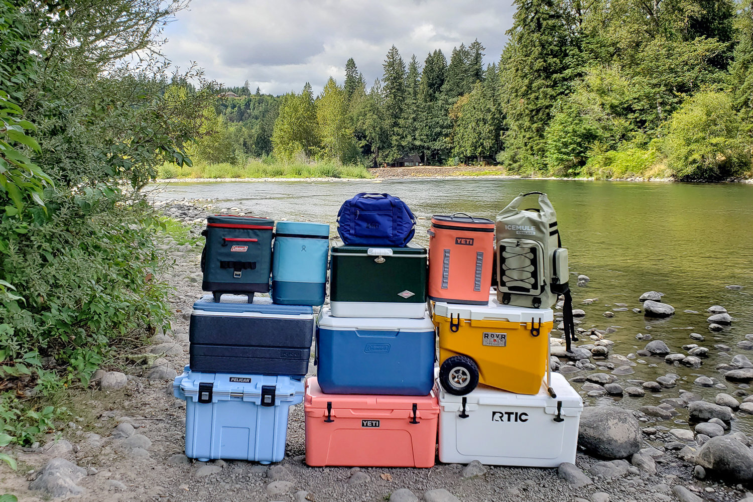 https://www.cleverhiker.com/wp-content/uploads/2023/08/A-stack-of-the-best-coolers-on-the-market-in-front-of-a-river-in-the-Pacific-Northwest.jpeg