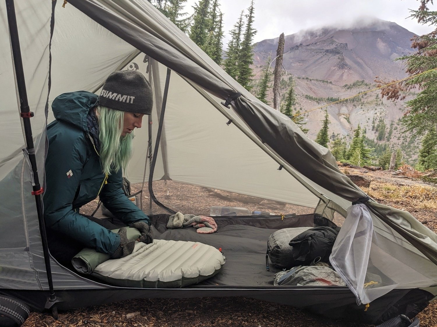 a women packs up her tent on a cold morning by first deflating her therm-a-rest before exiting the tent