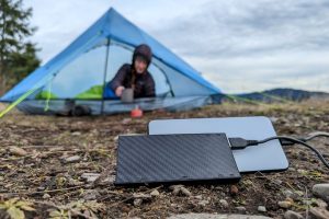 backpacker in their tent with their portable charger charging on the ground