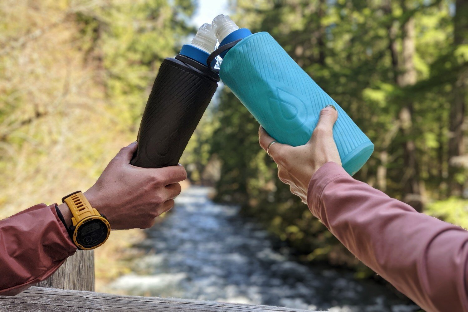 https://www.cleverhiker.com/wp-content/uploads/2023/08/Two-hands-doing-a-cheers-with-Hydrapak-Flux-water-bottles.jpeg