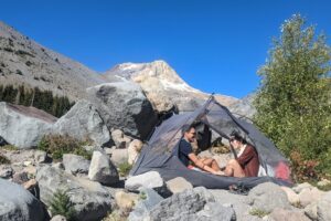 two backpackers below a volcano in oregon sitting inside their sea to summit telos tent without the rain fly