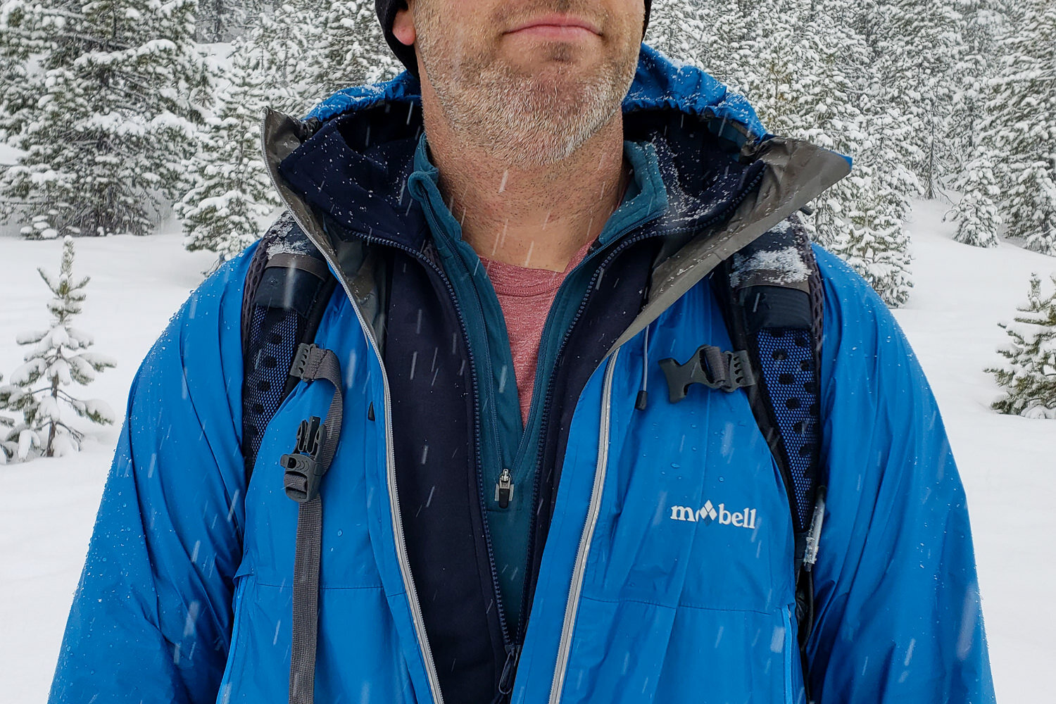 the chest of a backpacker in the snow with 4 layers on unzipped for viewing and dumping heat