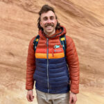 Ian Krammer profile photo with him smiling on a hiking trip with a canyon wall in the background