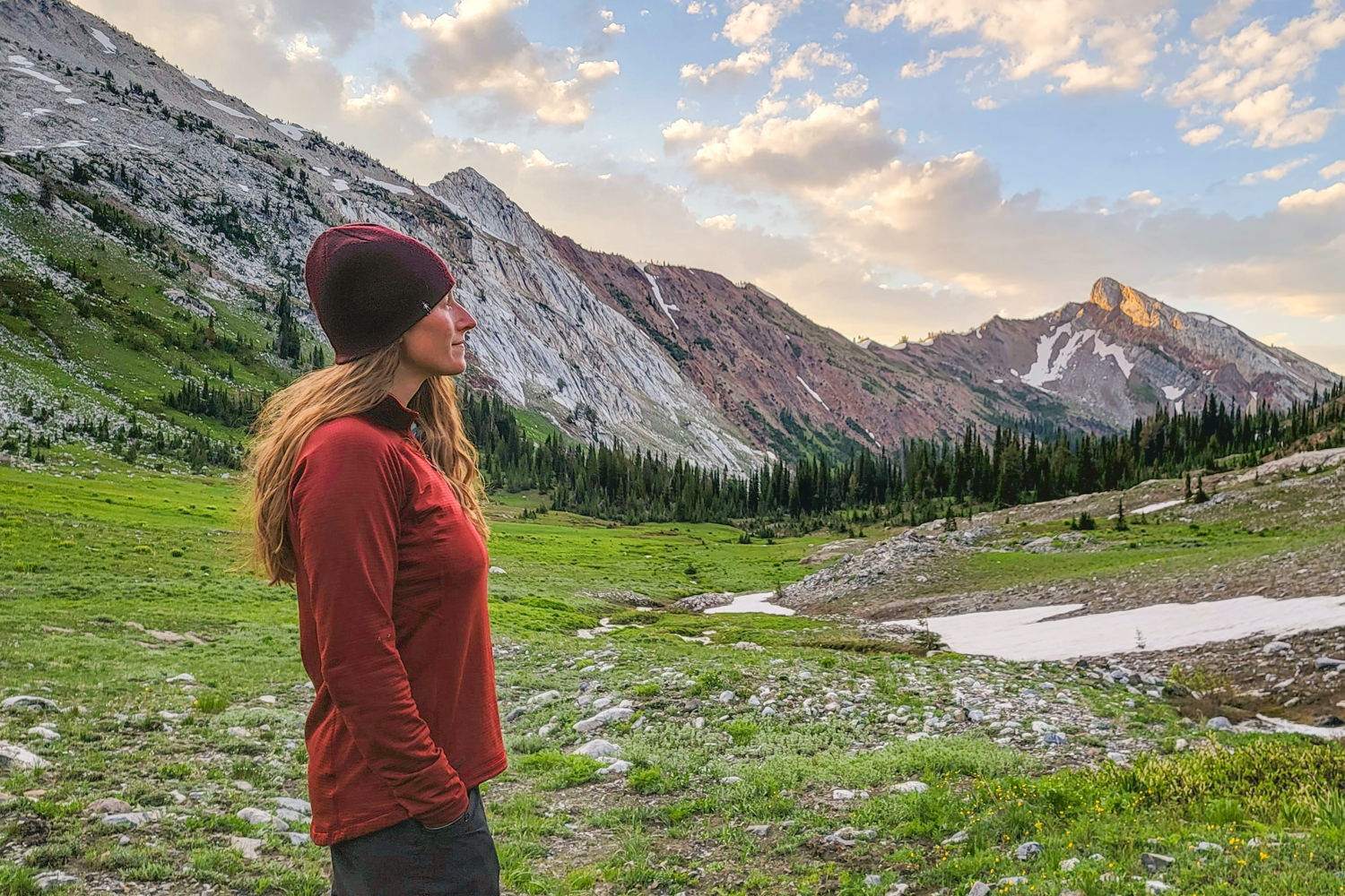 A woman wearing a red Outdoor Research Vigor fleece pullover in a granite mountain-lined valley