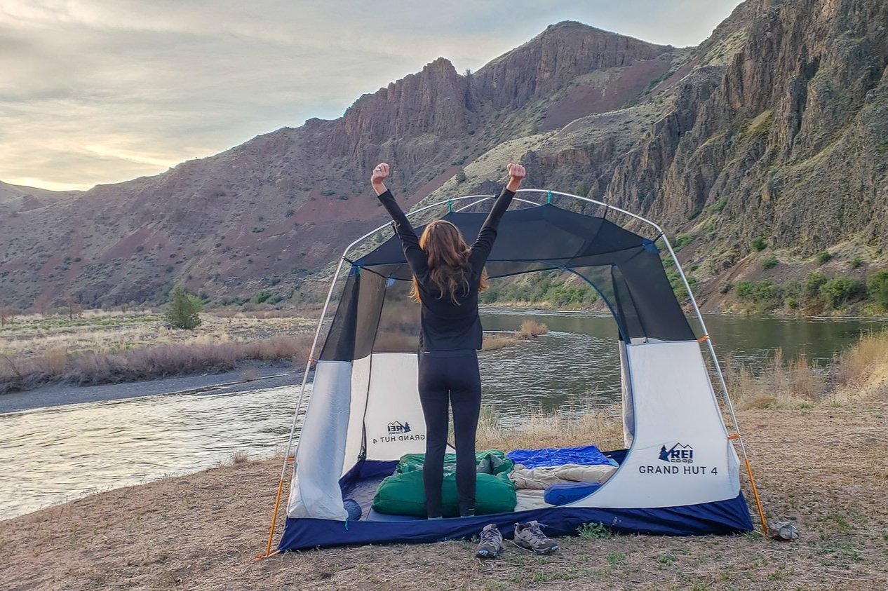 A camper stretching her arms overhead in the Patagonia Capilene Midweight Base Layer Top