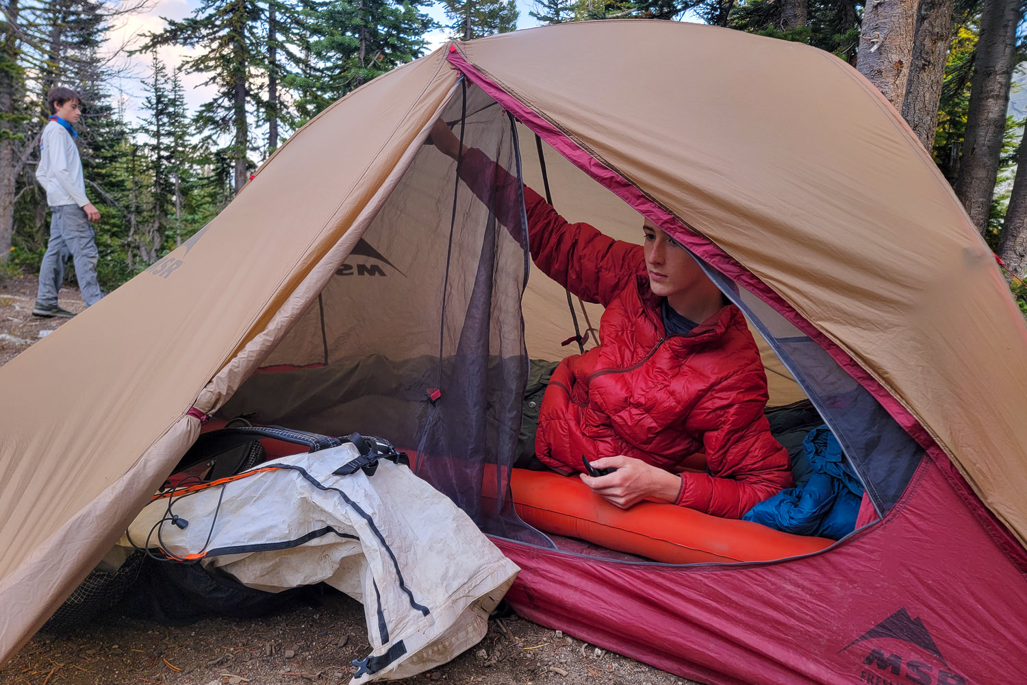 a backpacker inside their tent unzipping the mesh door