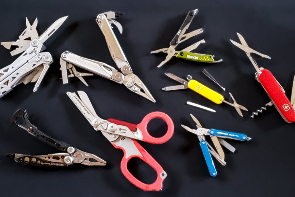Top-down view of a variety of colorful multitools on a black background