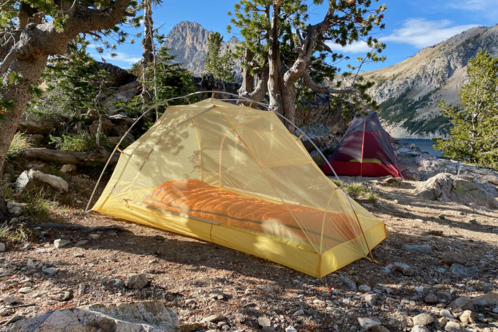 A tent setup in a campsite with no fly on and mountains in the background.