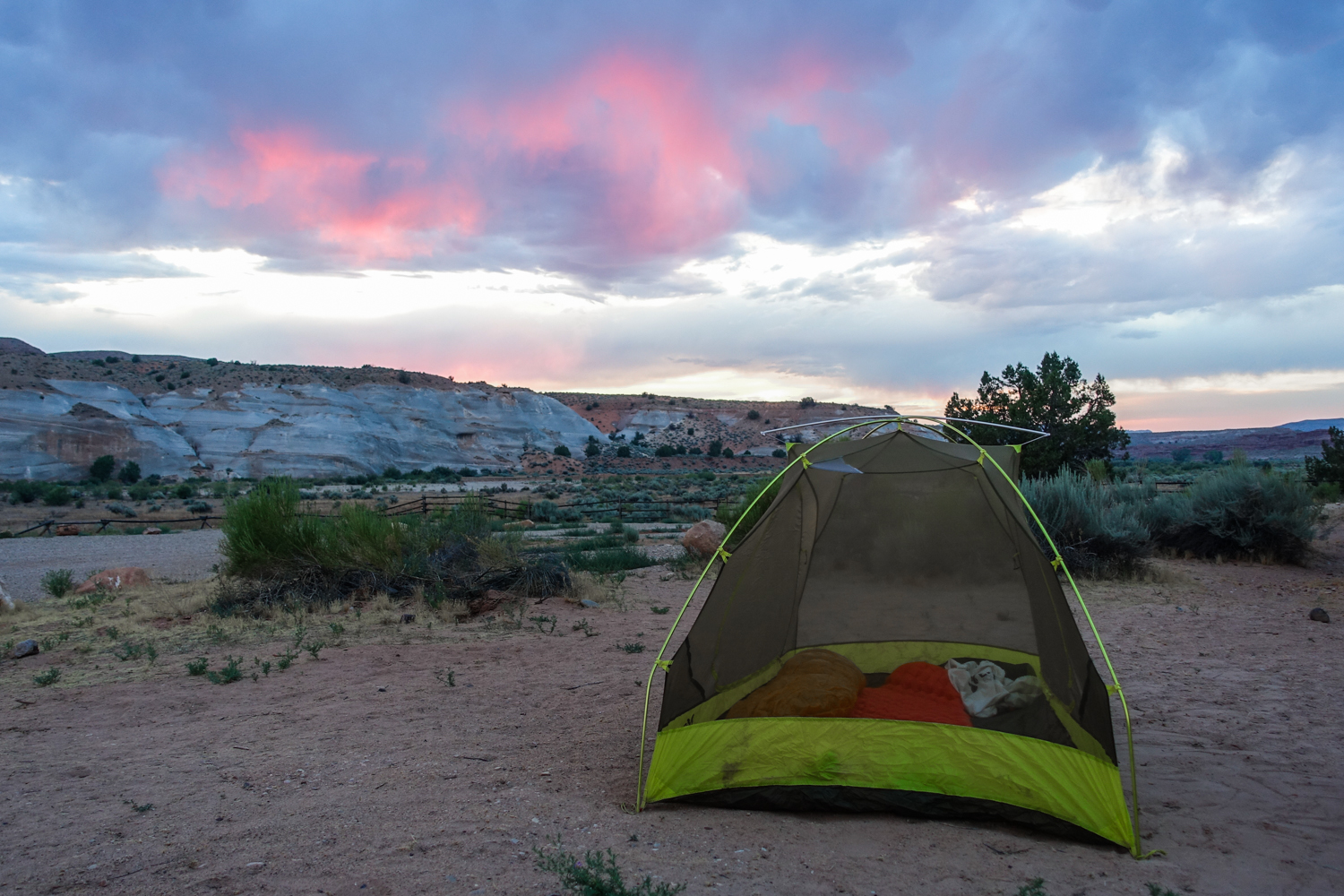 the desert pink and blue clouded sunrise over a green tent