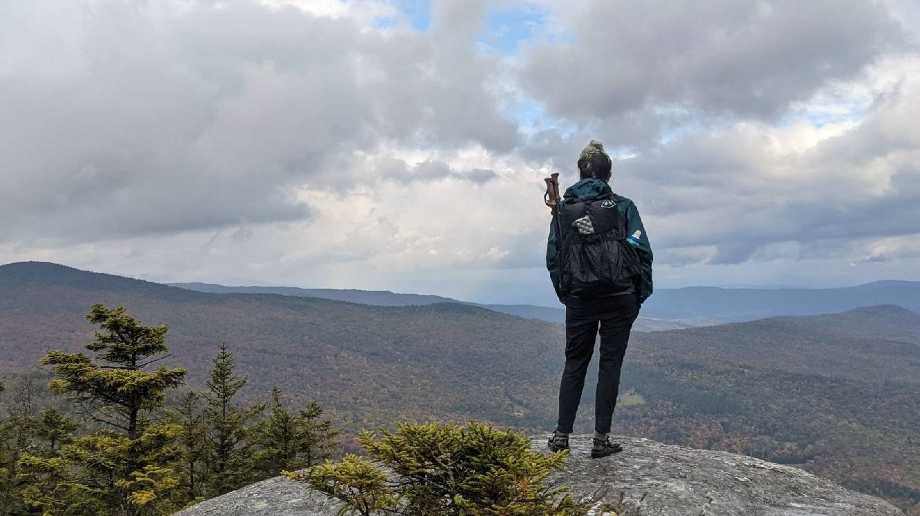 AT thru-hiker looks over a vista on a cloudy day