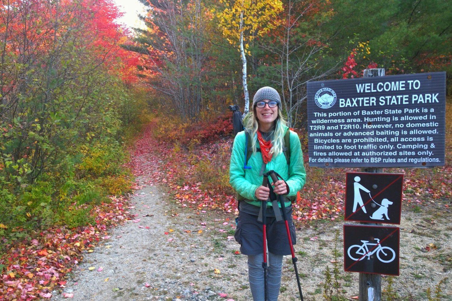 Appalachian Trail thru-hiker stands at the entrance of Baxter State Park in Maine in the fall