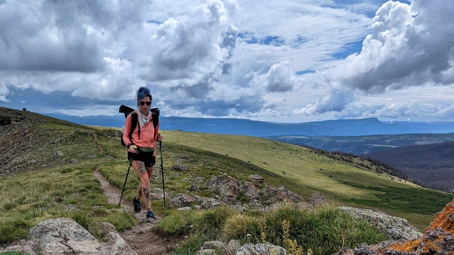 thru-hiker on an open bench on the colorado trail with clouds and sunshine.