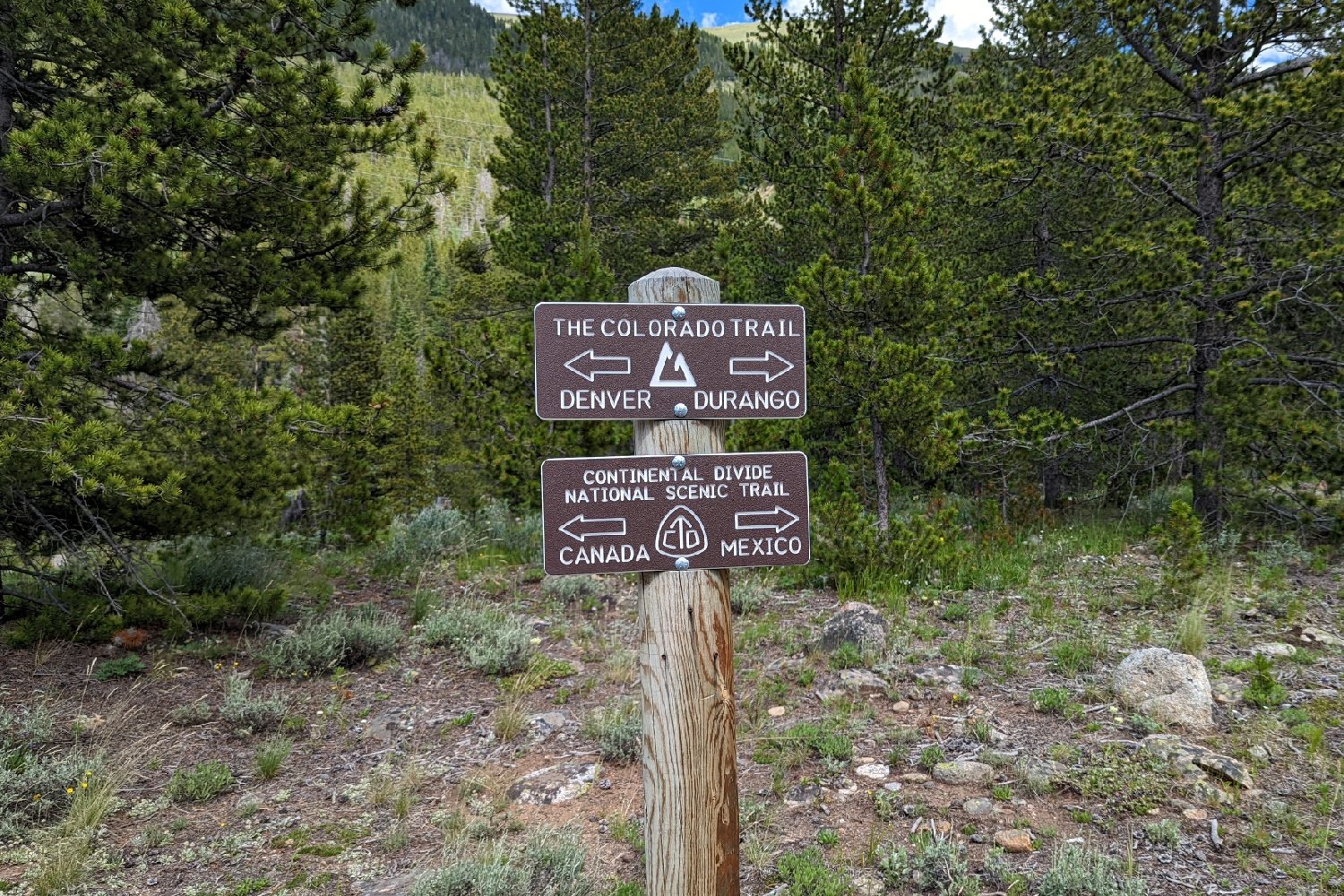 trail sign for the colorado indicating left to durango, right arrow to denver and another sign below indicating left arrow to mexico, right arrow to canada for the continental divide trail 