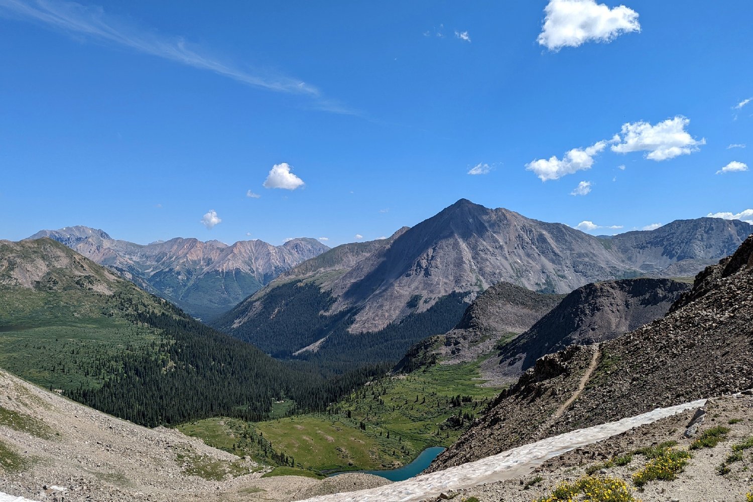 mountain range with blue skies and a lake at the bottom along the colorado trail