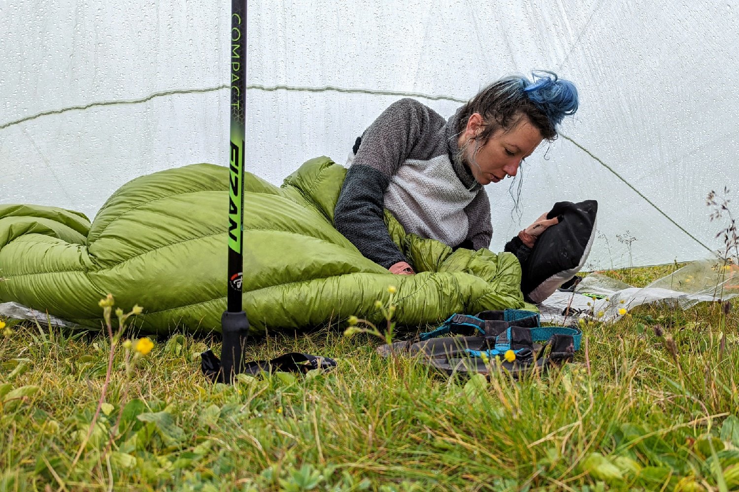 backpacker on the colorado trail under her tarp on the ground in a sleeping bag in the rain