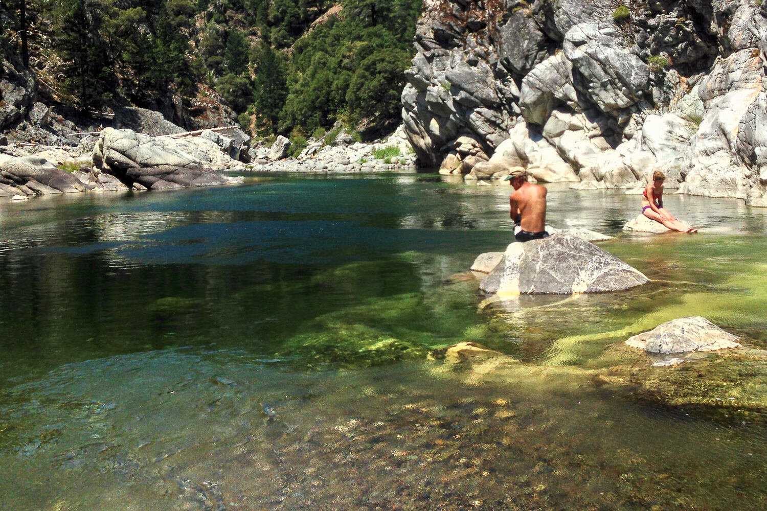 Hikers taking a swim break in a deep, clear slow river