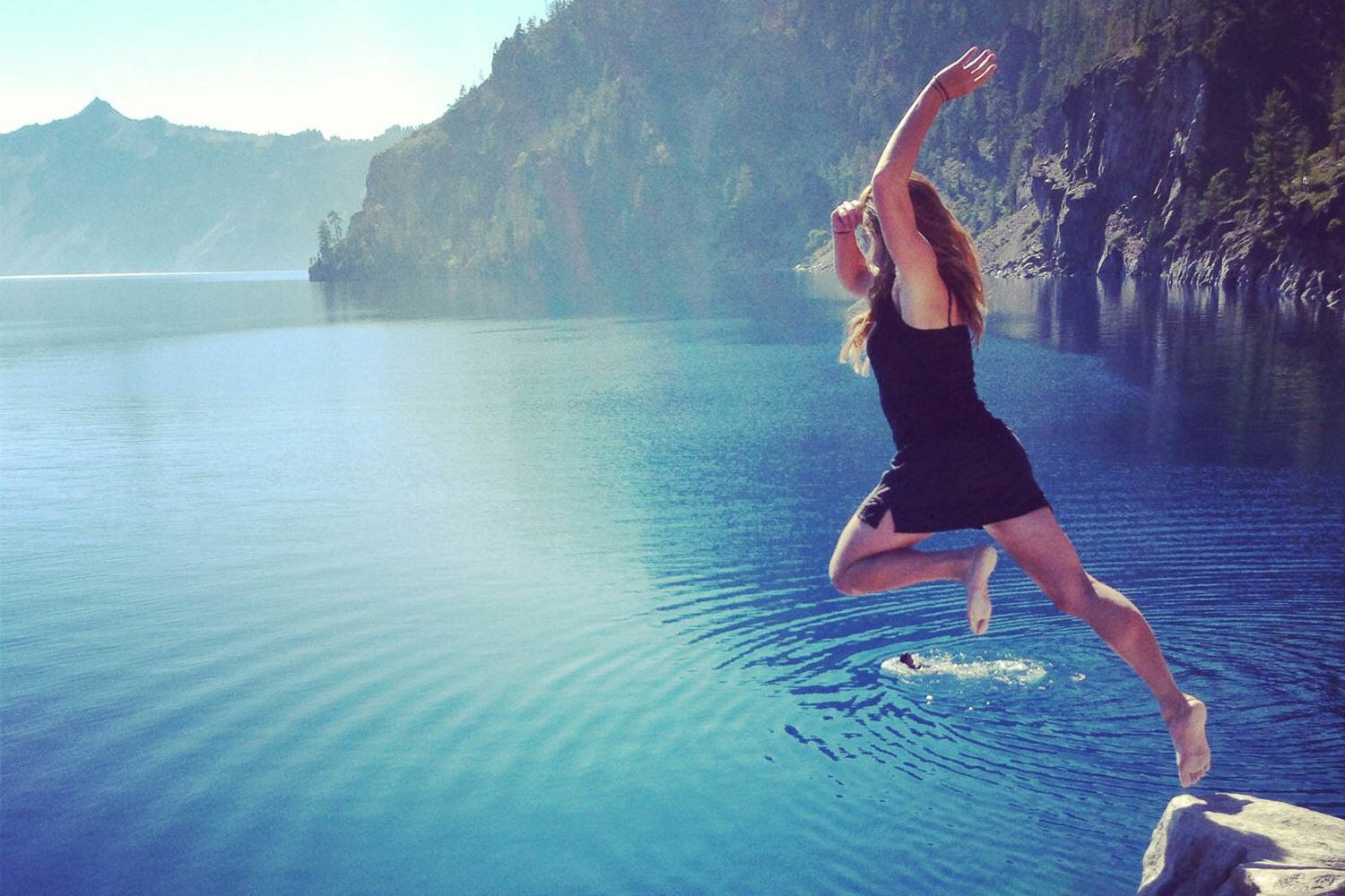 Hiker jumping into a lake on s sunny day