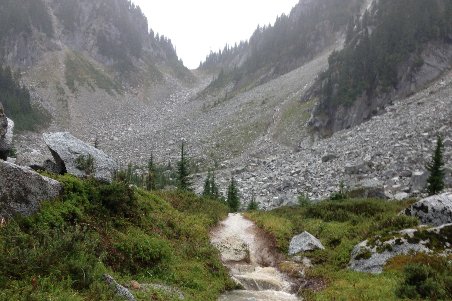 mountain pass and scree field with stream in the foreground.