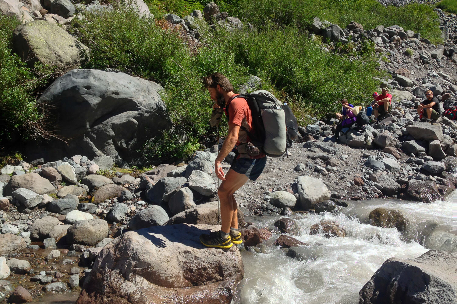 thru-hiker crossing a stream with friends watching