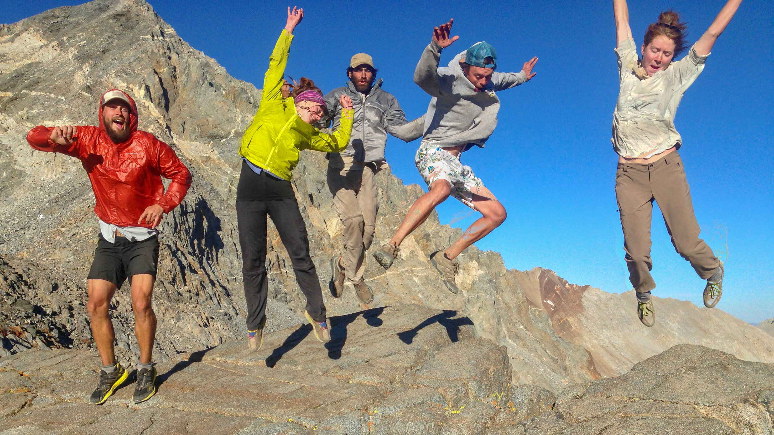 Hikers photographed in mid-air on a rocky trail on a sunny day