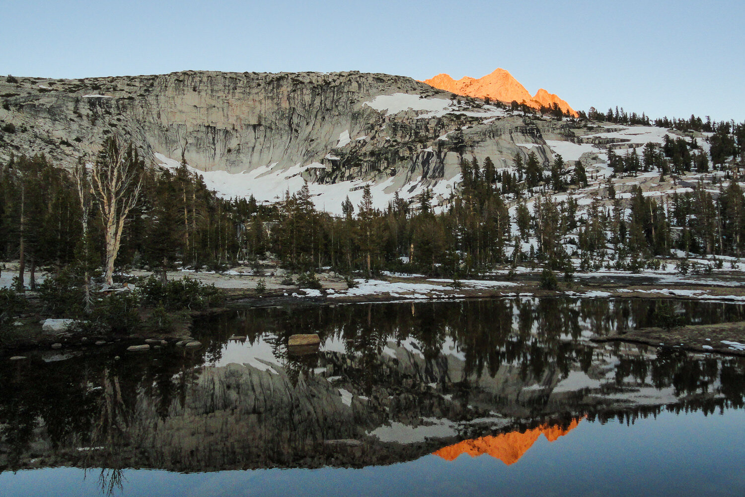 sunset on a snow spotted alpine lake.