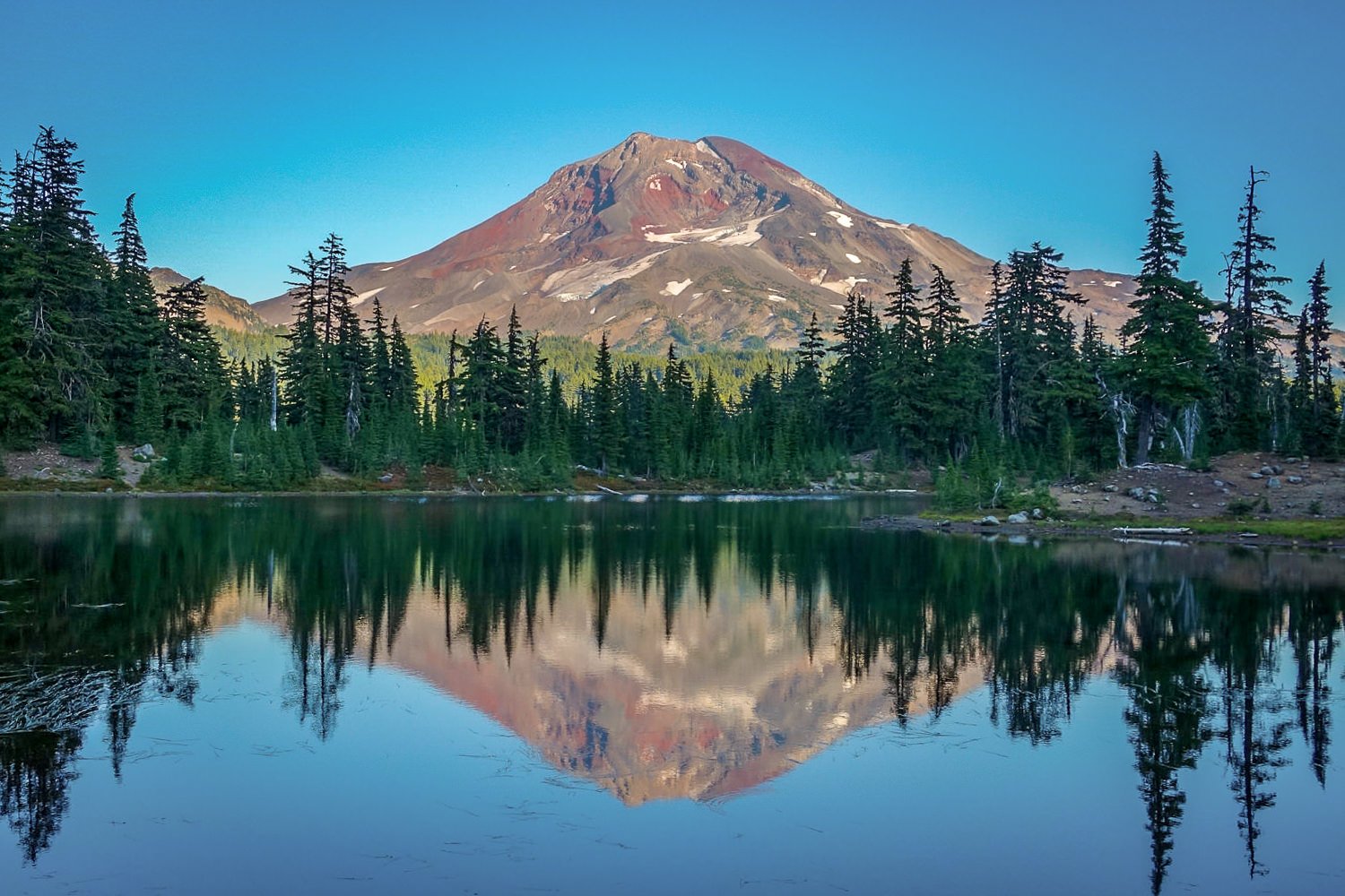 south sister volcano reflected in green lake in oregon