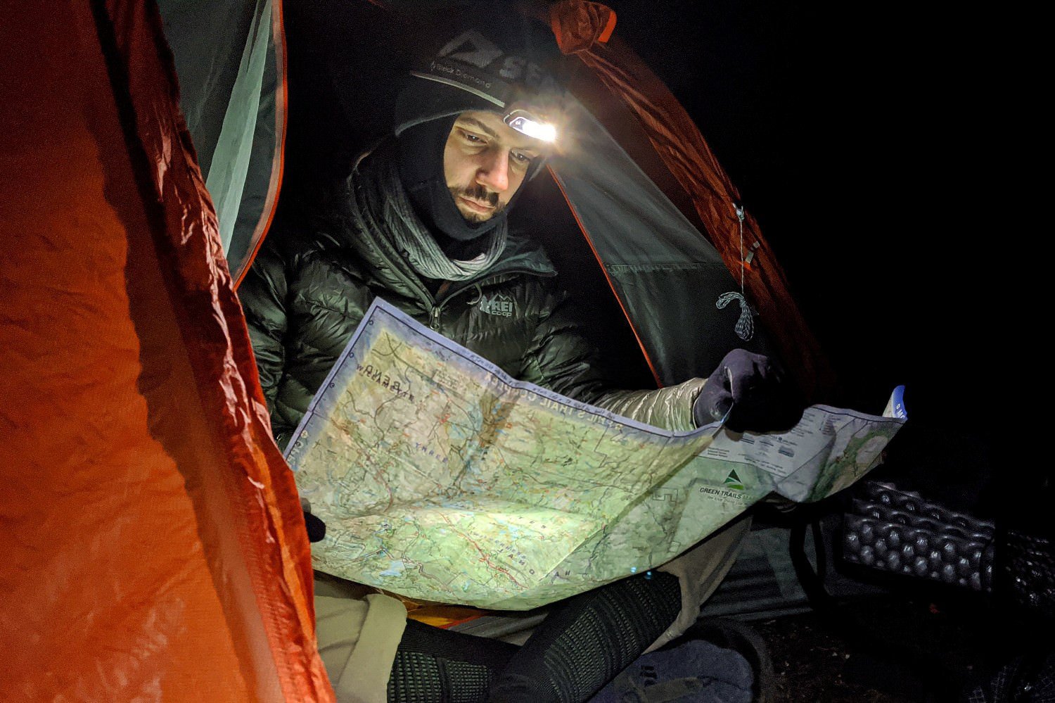 backpacker using their headlamp to read a topographical map while in their tent in the three sisters wilderness.