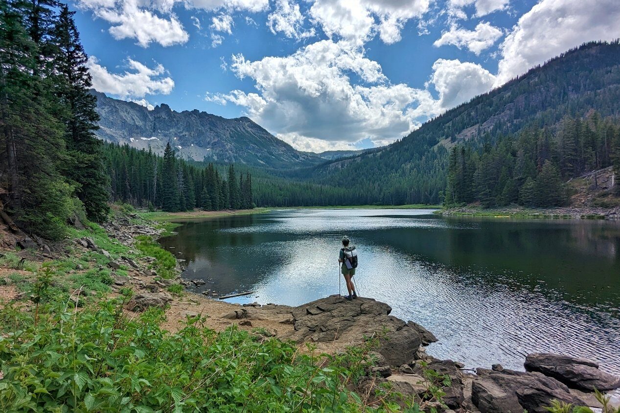 backpacker on the edge of strawberry lake in oregon on a sunny white puffy clouded day.