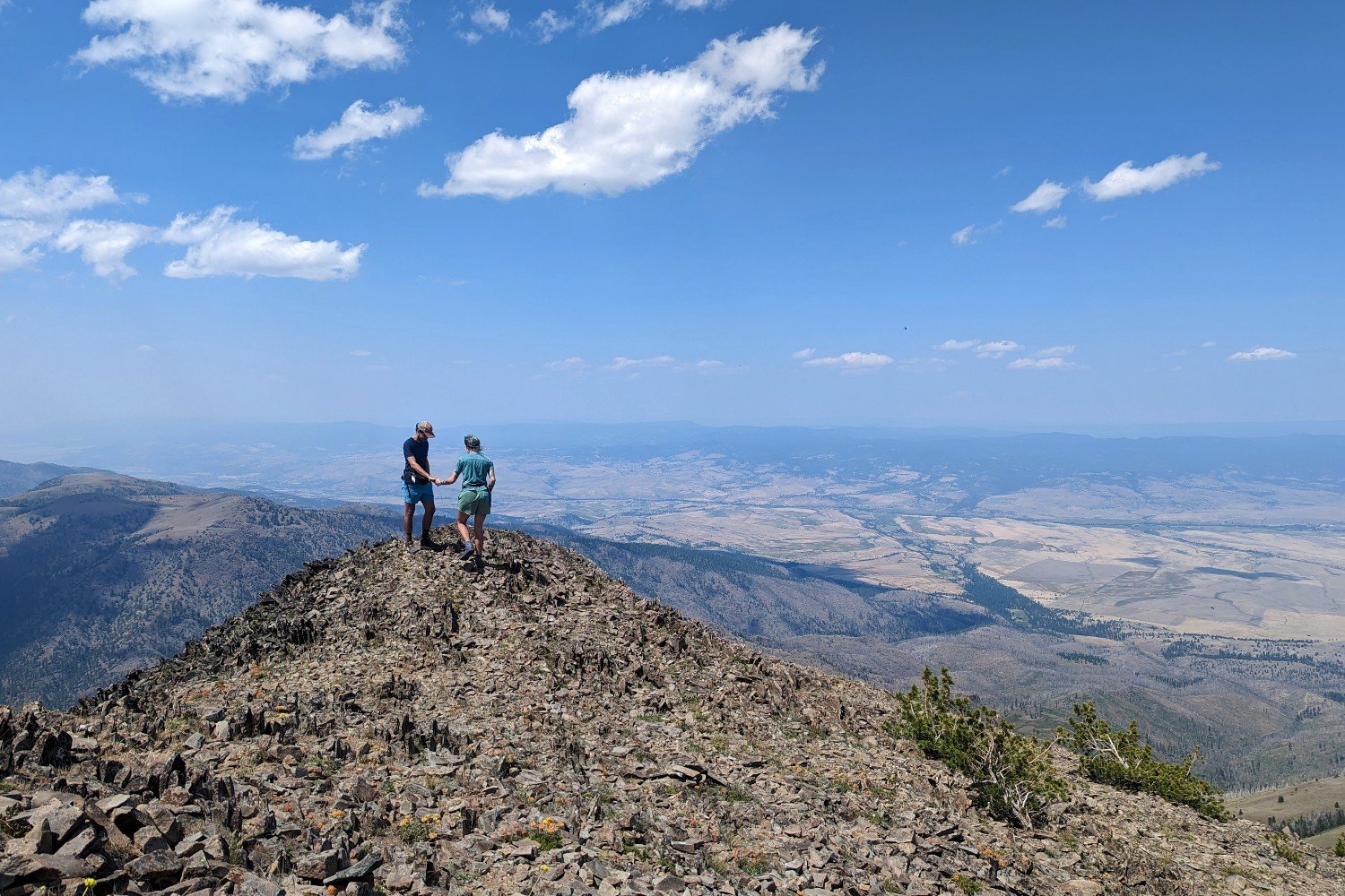 two backpackers summitting strawberry mountain in oregon. The summit is a pinkish beige scree top