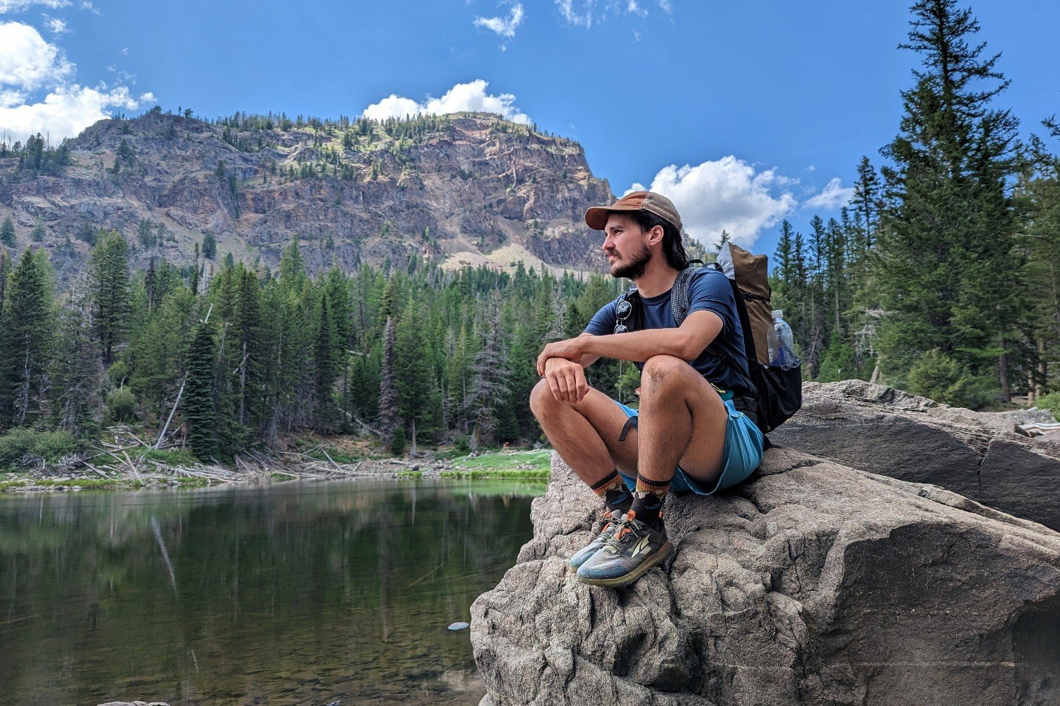 backpacker sitting on a boulder on the edge of a lake in the blue moutains in oregon