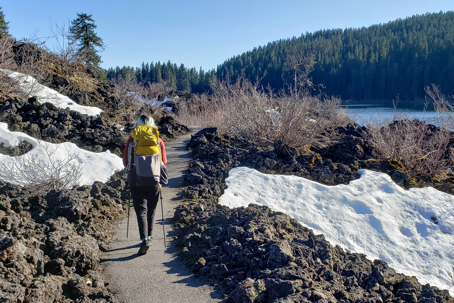 backpacker hiking through snow-covered lava rock and snow on the McKenzie river trail