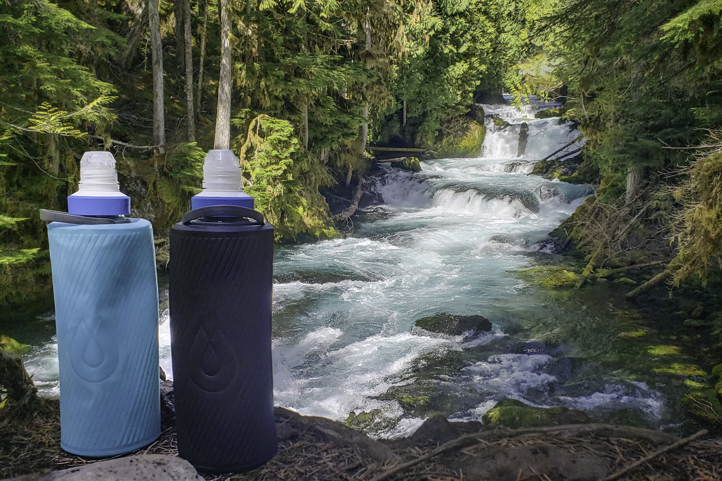 two water bottles and a water filter on a railing over the rapids and blue water of the mckenzie river