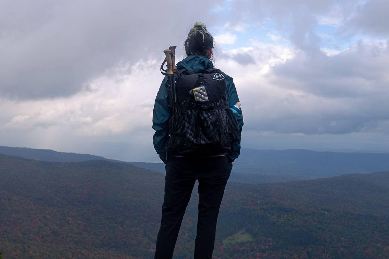 backpacker overlooking a rolling valley with clouds overhead. 