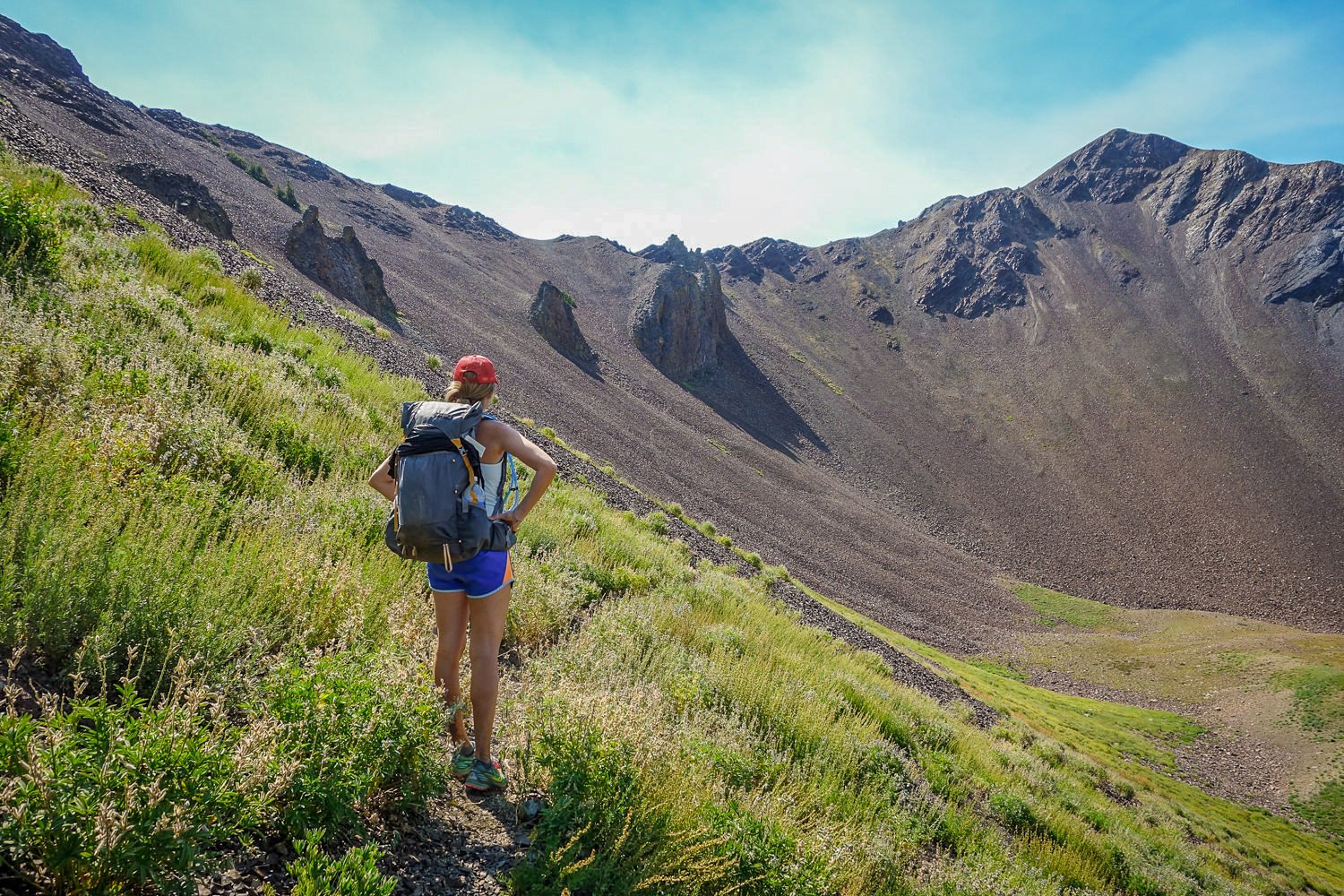 backpacker below a mountain pass in the wallowa mountain range in the eagle cap wilderness. The pass is a mixture of scree fields, meadows, and rocky crags. 