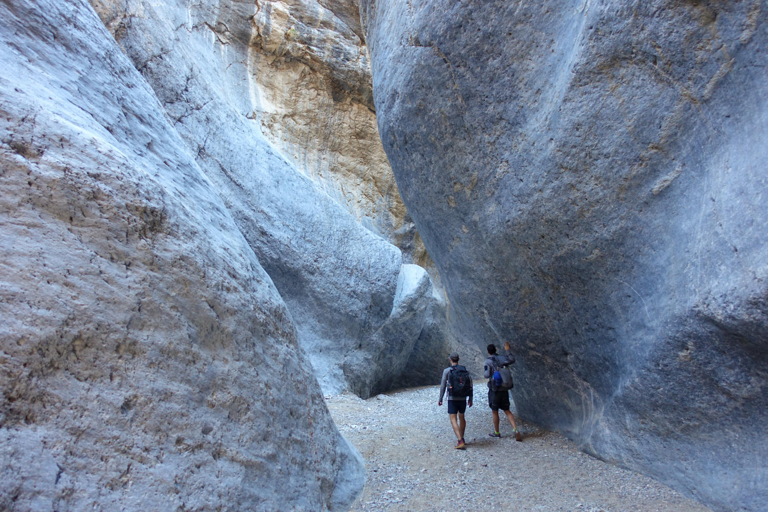 two backpackers on the cottonwood marble loop in death valley walking through a slot canyon