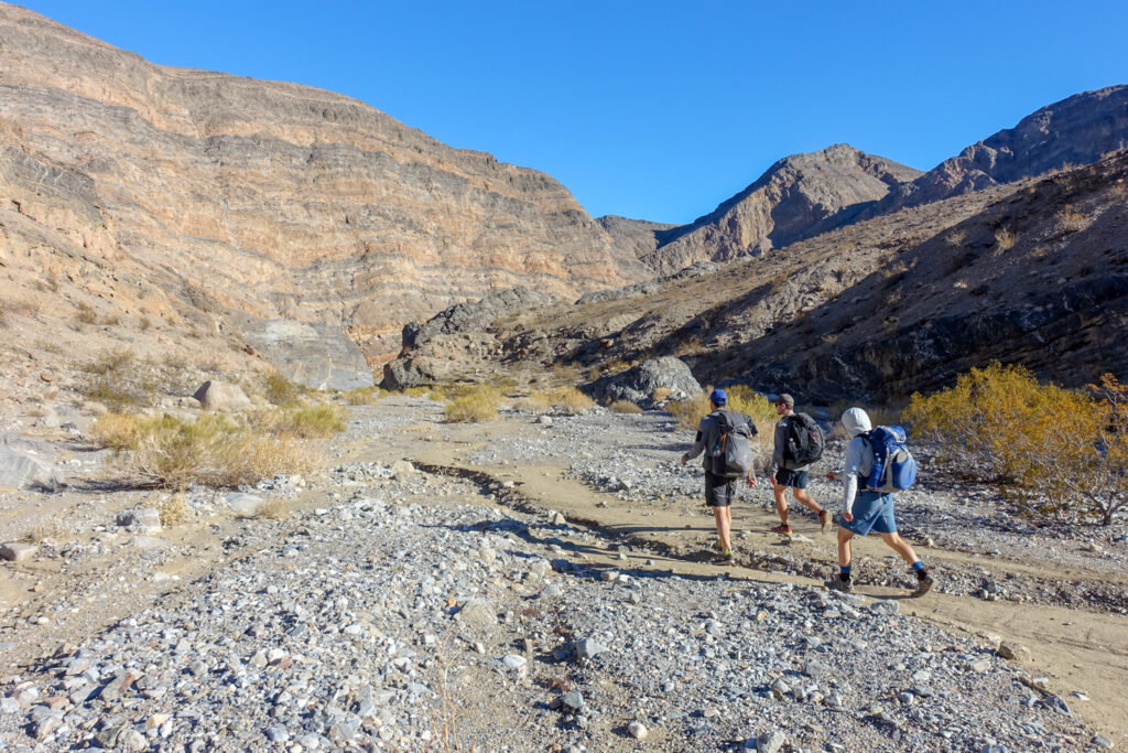 backpackers on the cottonwood marble canyon loop in death valley walking on a washout