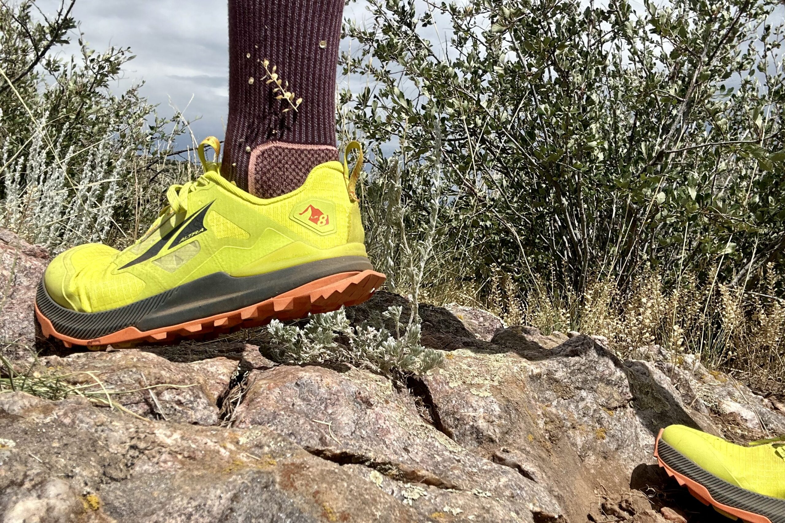 A close up of a hiker from the ankles down wearing trail runners in a desert setting.