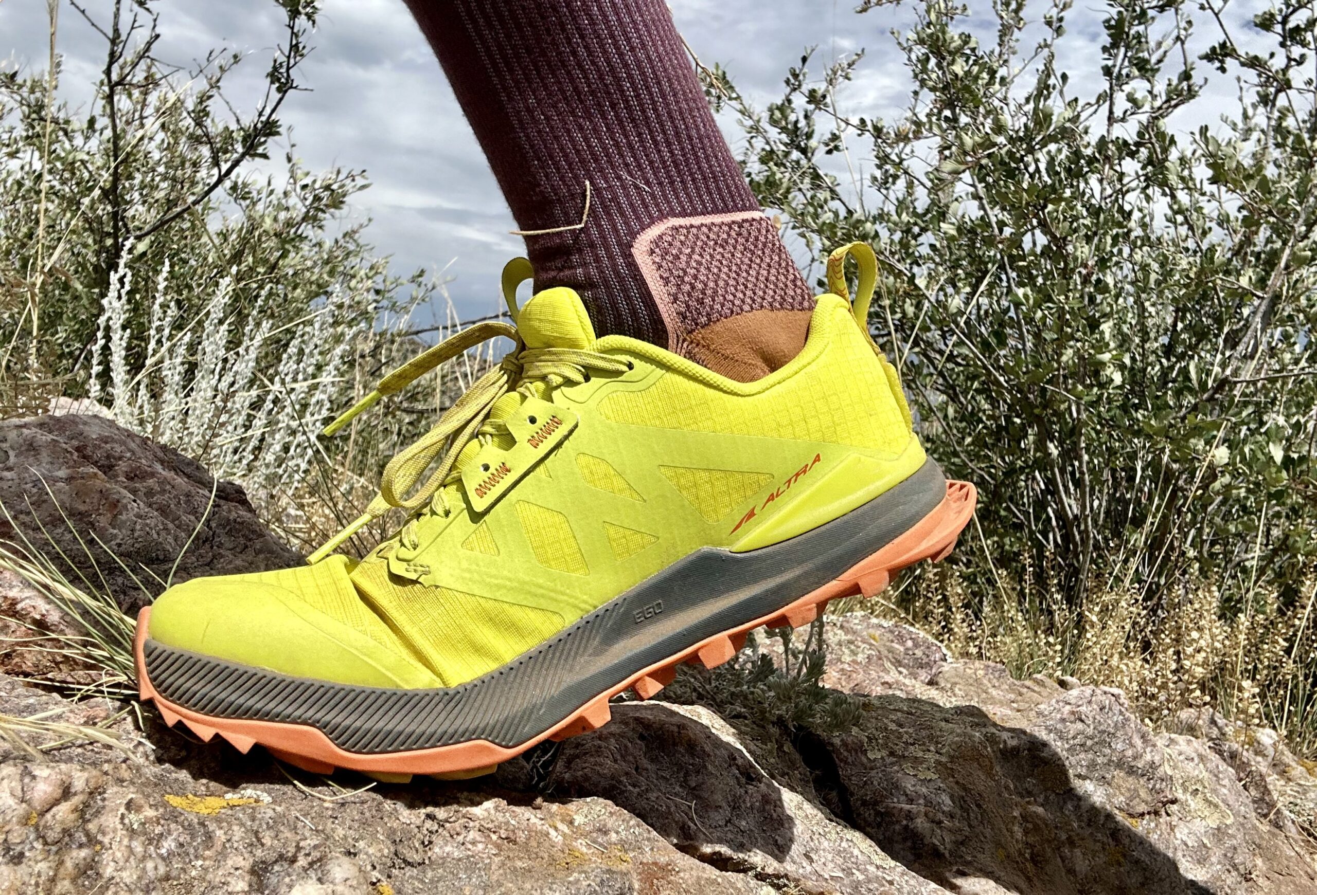A side profile shot of a hiker from the ankles down wearing trail runners in a desert setting.